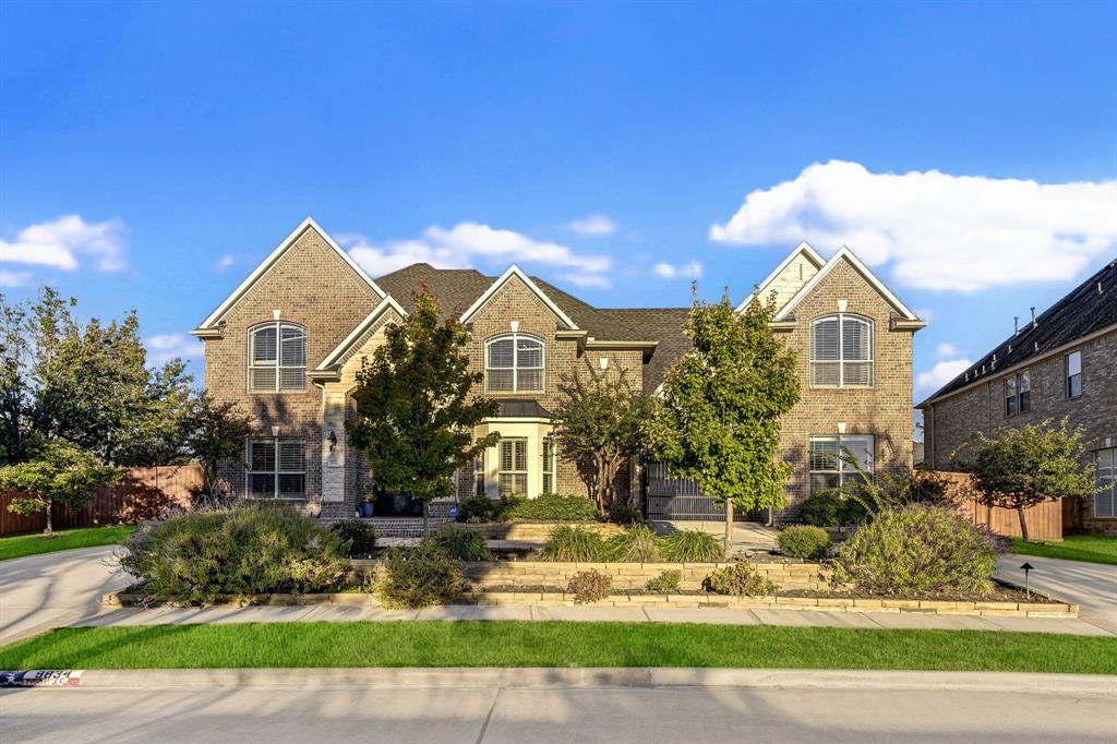 This stunning home sits majestically above the street. The elegant exterior of the house features a combination of classic stone and brick, with large windows and stately double doors.