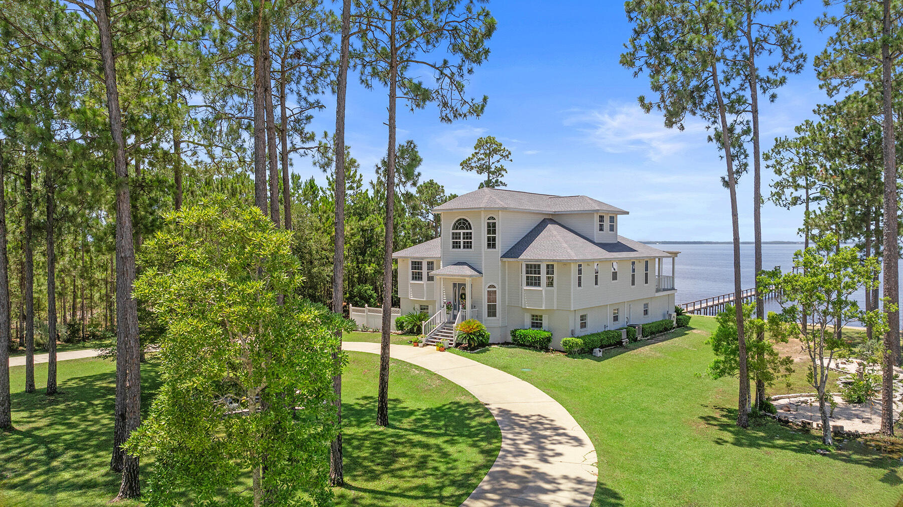 a view of a house with a big yard plants and large trees