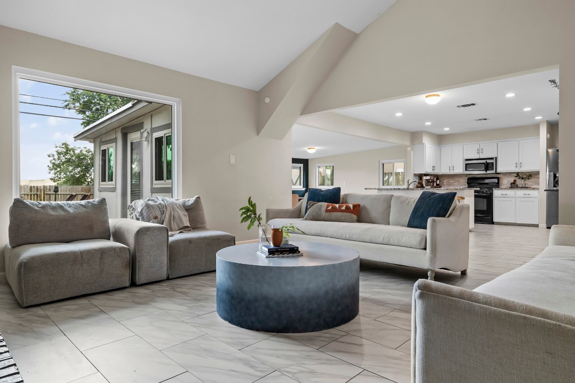 a living room with couches and kitchen view with wooden floor