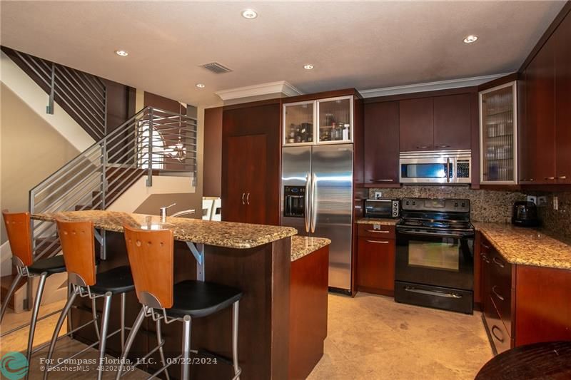 a kitchen with kitchen island granite countertop wooden cabinets and stainless steel appliances