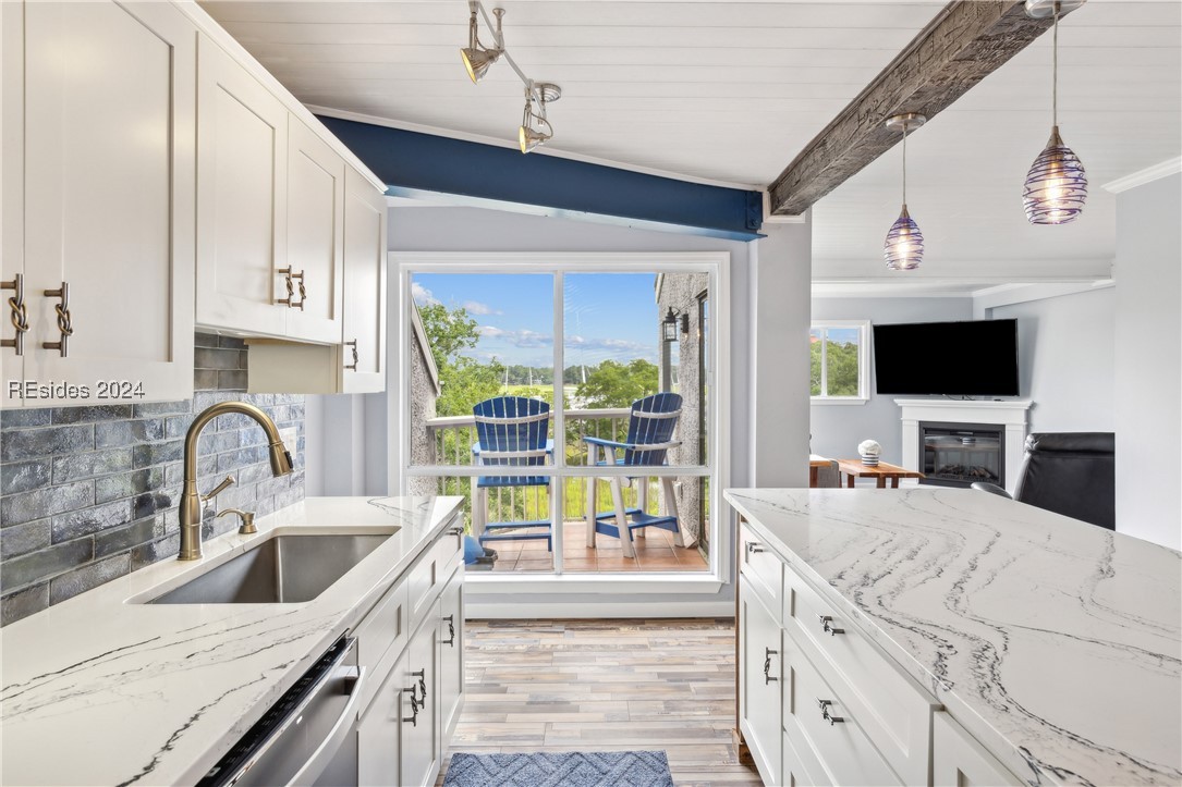 Kitchen featuring white cabinetry, light stone cou