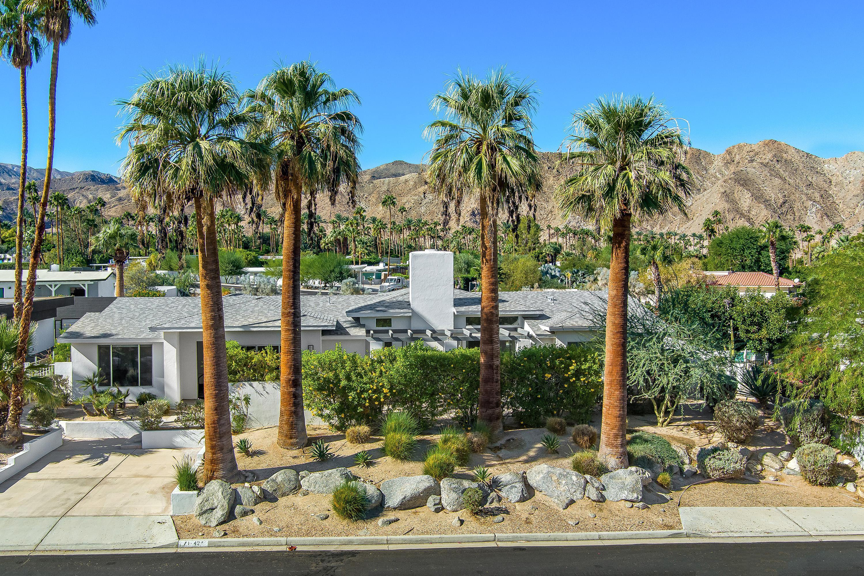 front view of a house with a yard and palm trees