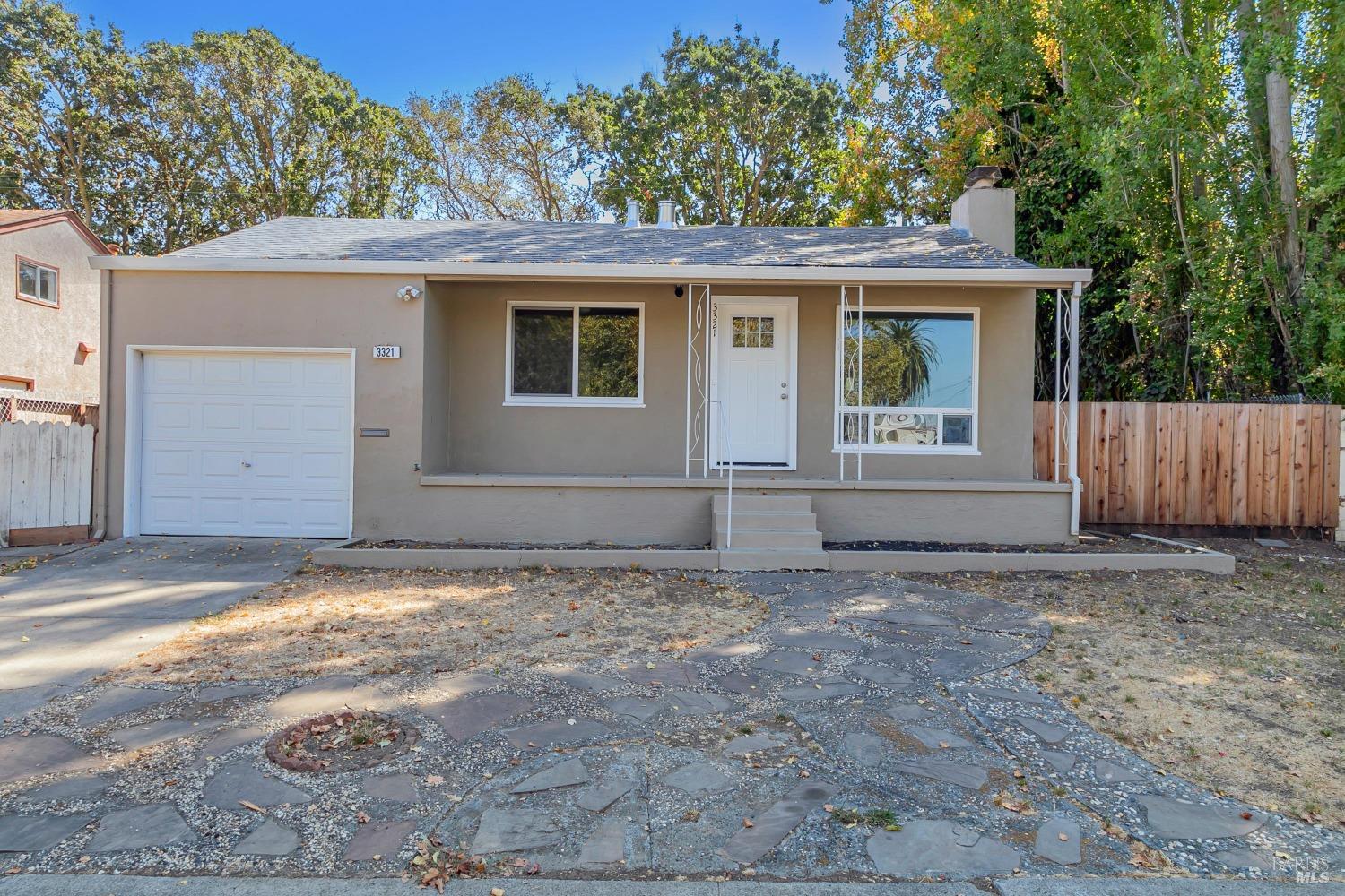 a view of a house with a small yard and large tree