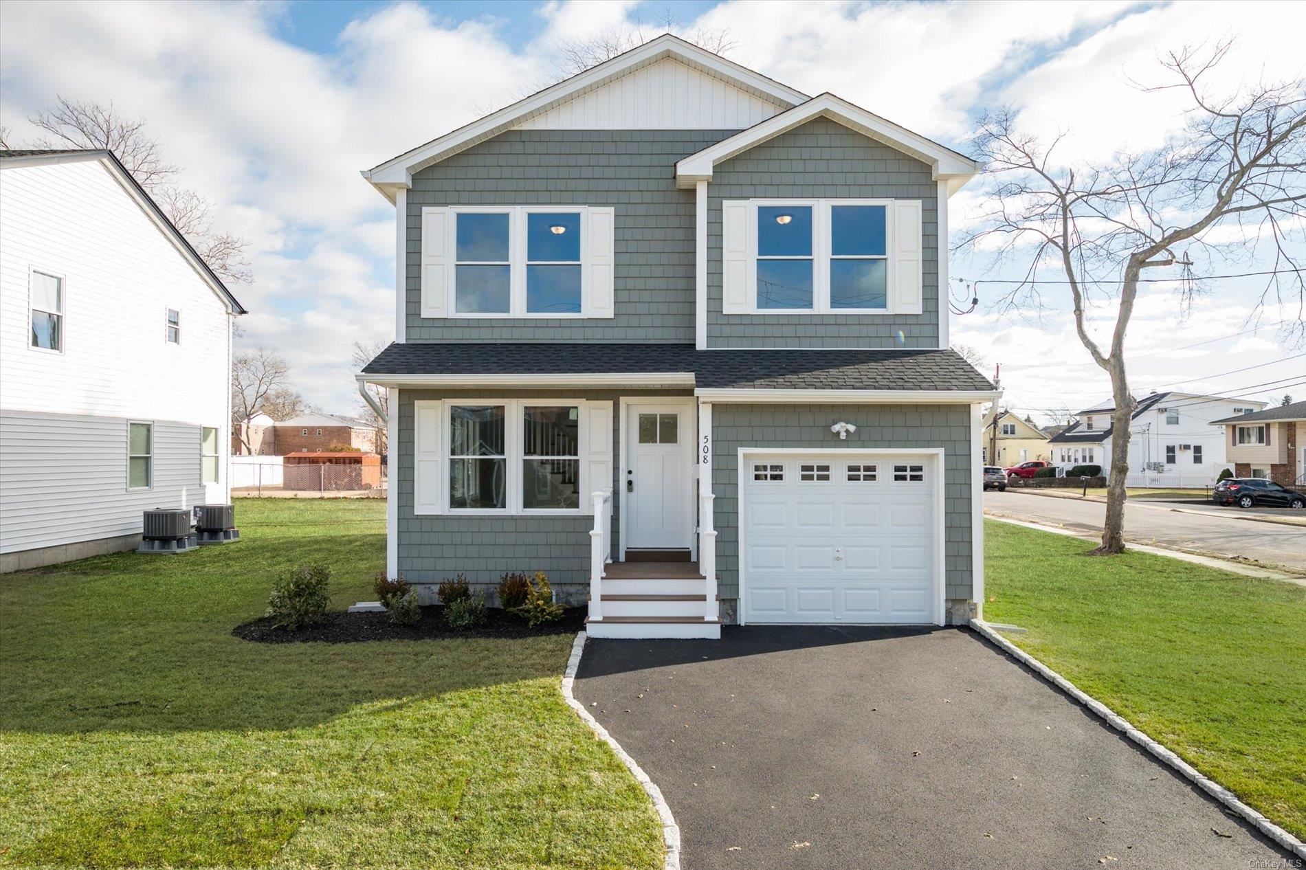 View of front of home featuring central air condition unit, a front lawn, and a garage