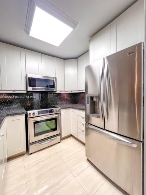 a kitchen with stainless steel appliances granite countertop a refrigerator a stove a sink and a microwave