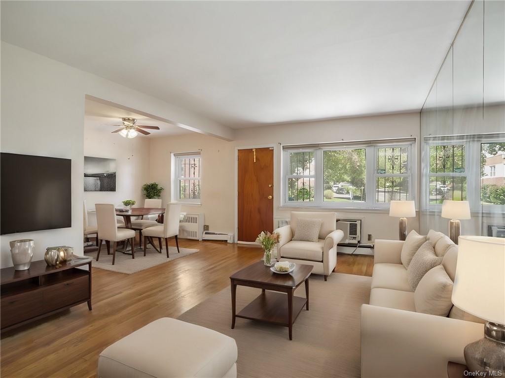 Virtually Staged -Living room with a baseboard radiator, an AC wall unit, light hardwood / wood-style floors, and ceiling fan