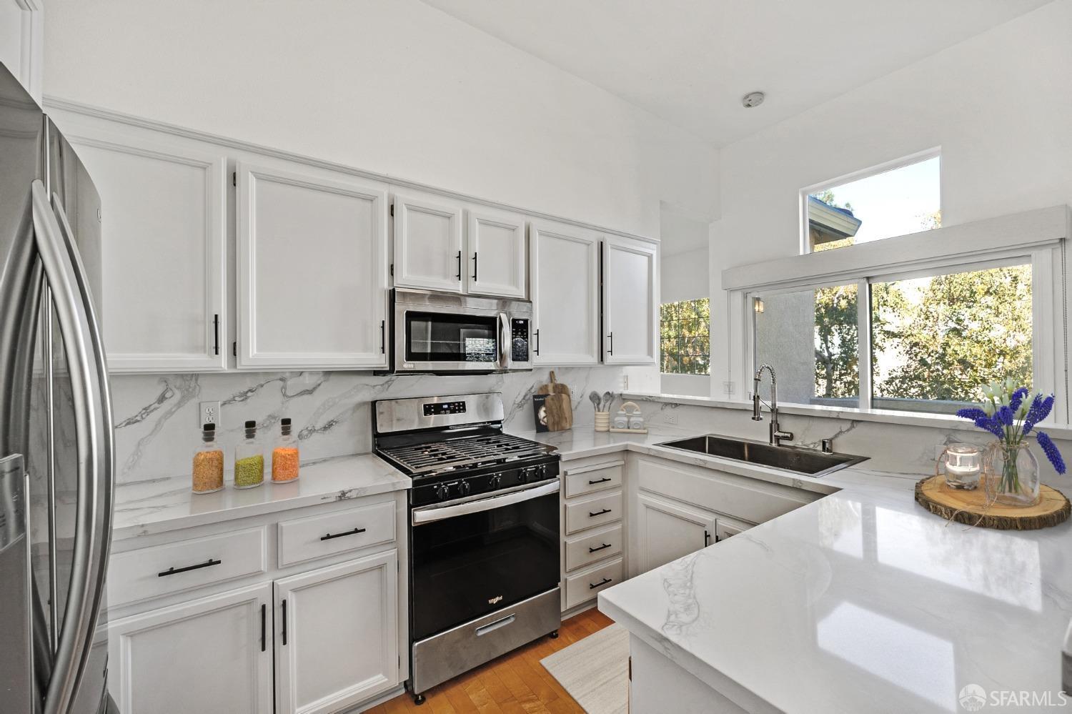 a kitchen with stainless steel appliances a stove a sink a stove and white cabinets