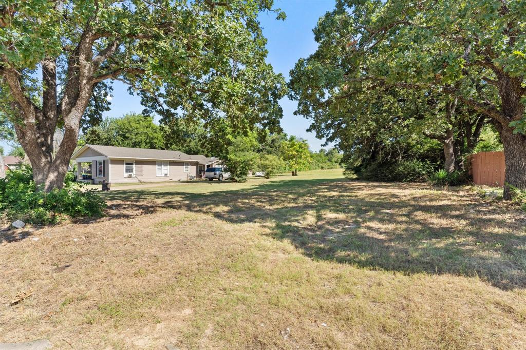 a backyard of a house with large trees and covered with wooden fence