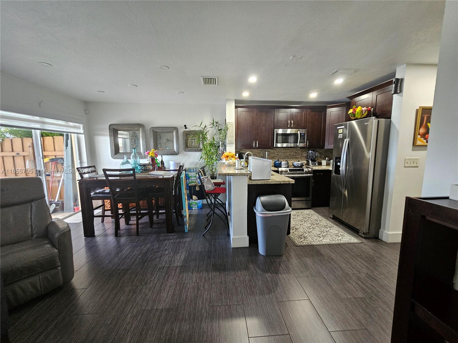 a kitchen with stainless steel appliances a dining table wooden floor and a refrigerator