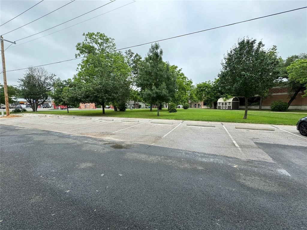 a view of a road with a big yard and large trees