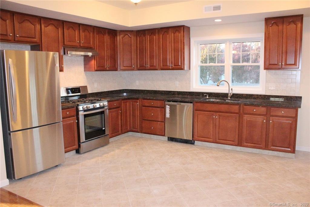 a kitchen with stainless steel appliances granite countertop a stove a refrigerator and a sink