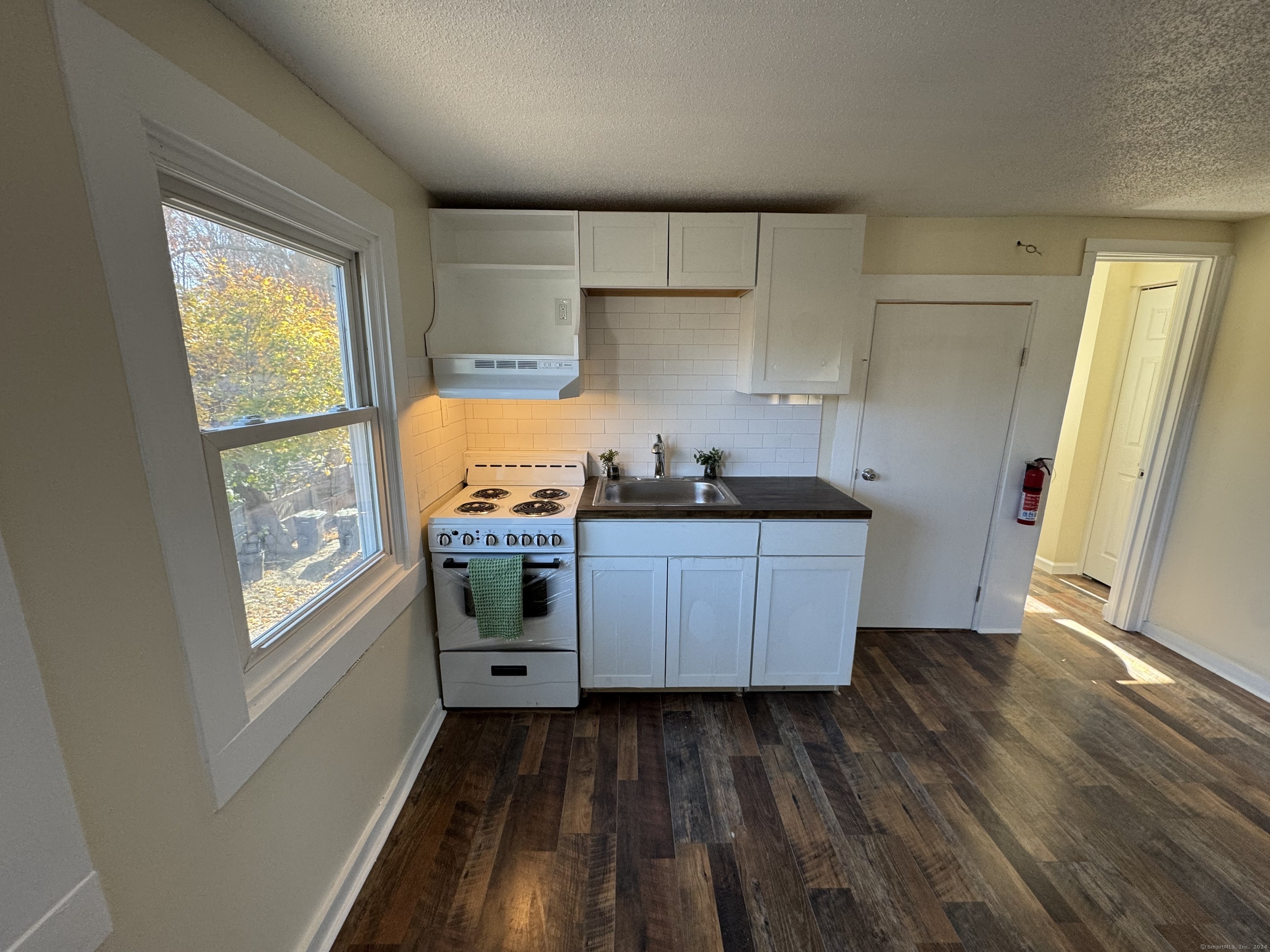 a kitchen with granite countertop white cabinets and wooden floors