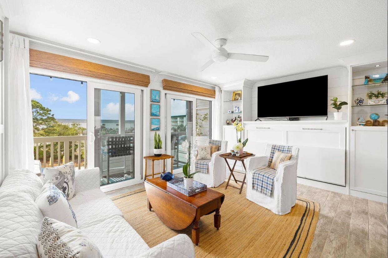 a living room with furniture a flat screen tv and a floor to ceiling window