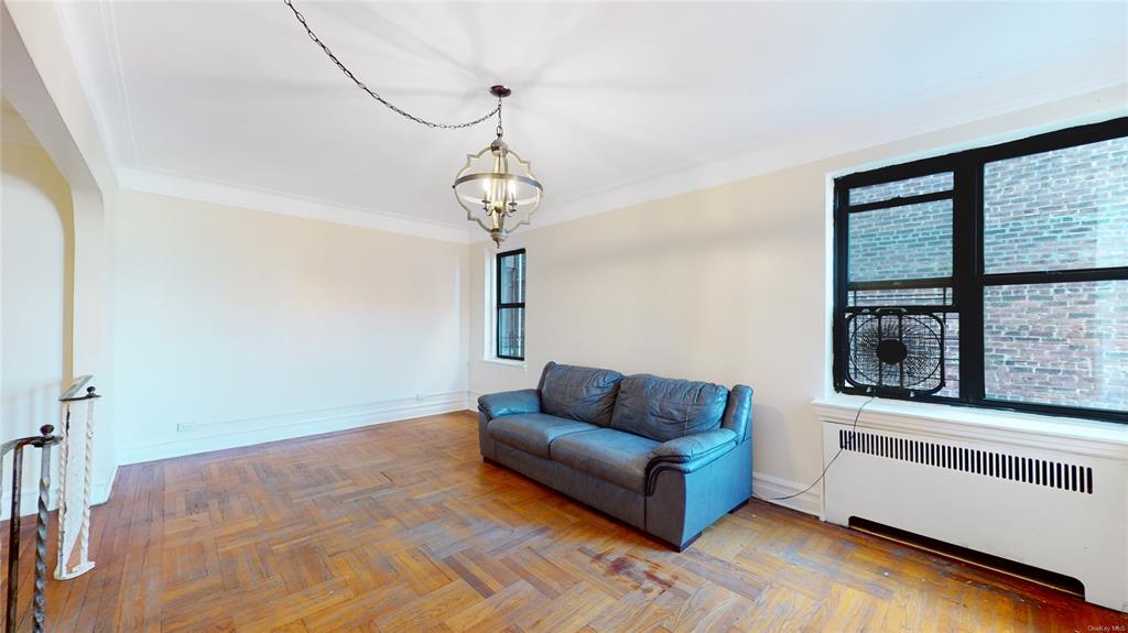 Sitting room featuring radiator, parquet floors, ornamental molding, and an inviting chandelier