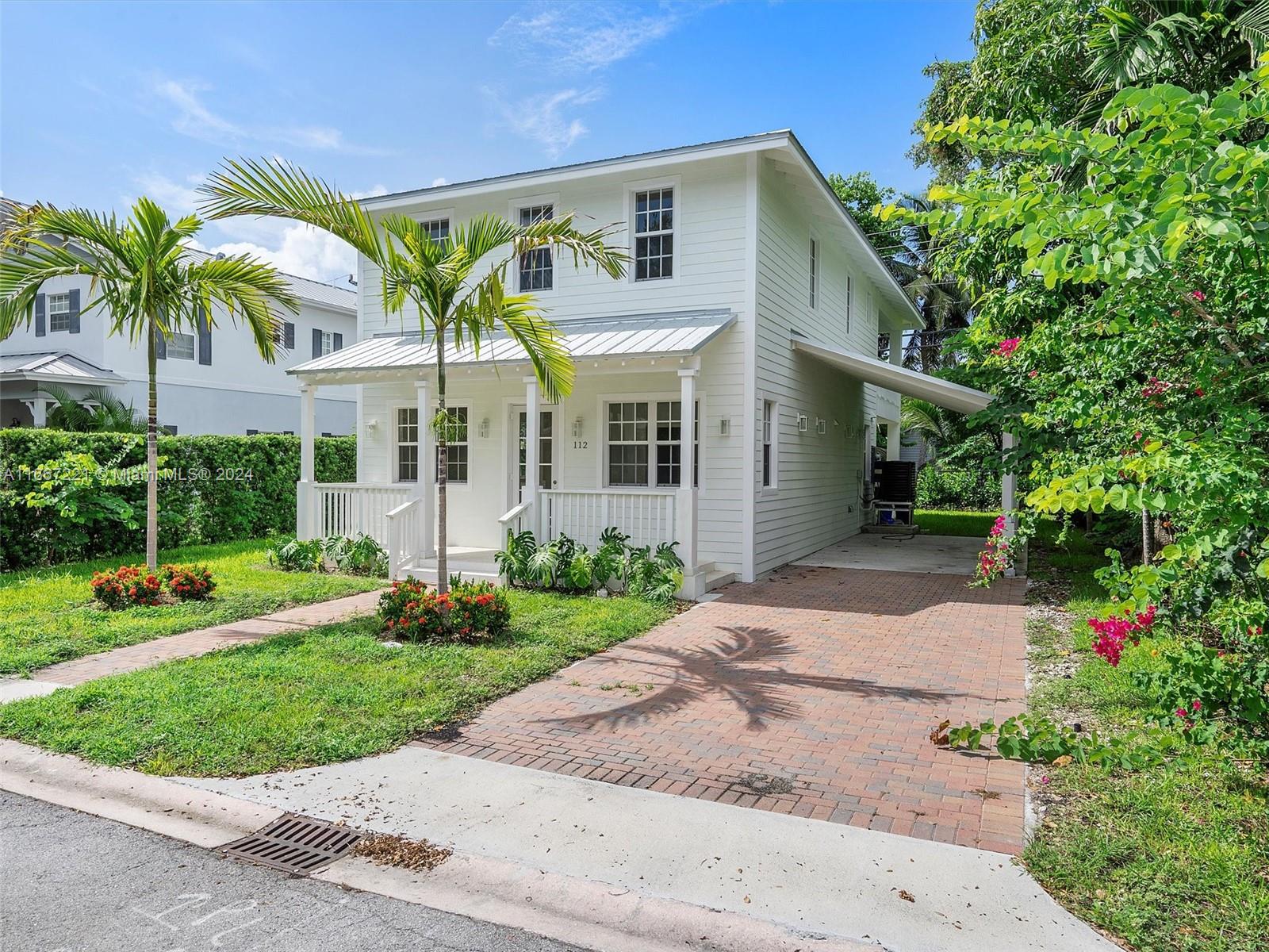 a view of a white house with a yard and potted plants