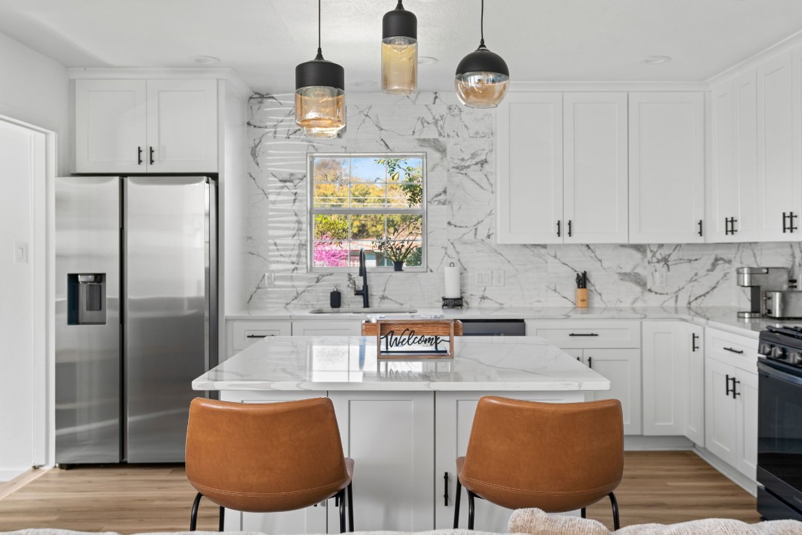 a kitchen with stainless steel appliances granite countertop a sink refrigerator and cabinets