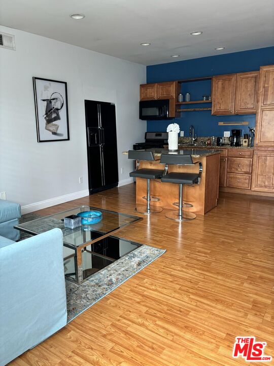 a living room with stainless steel appliances furniture a kitchen view and a kitchen counter top