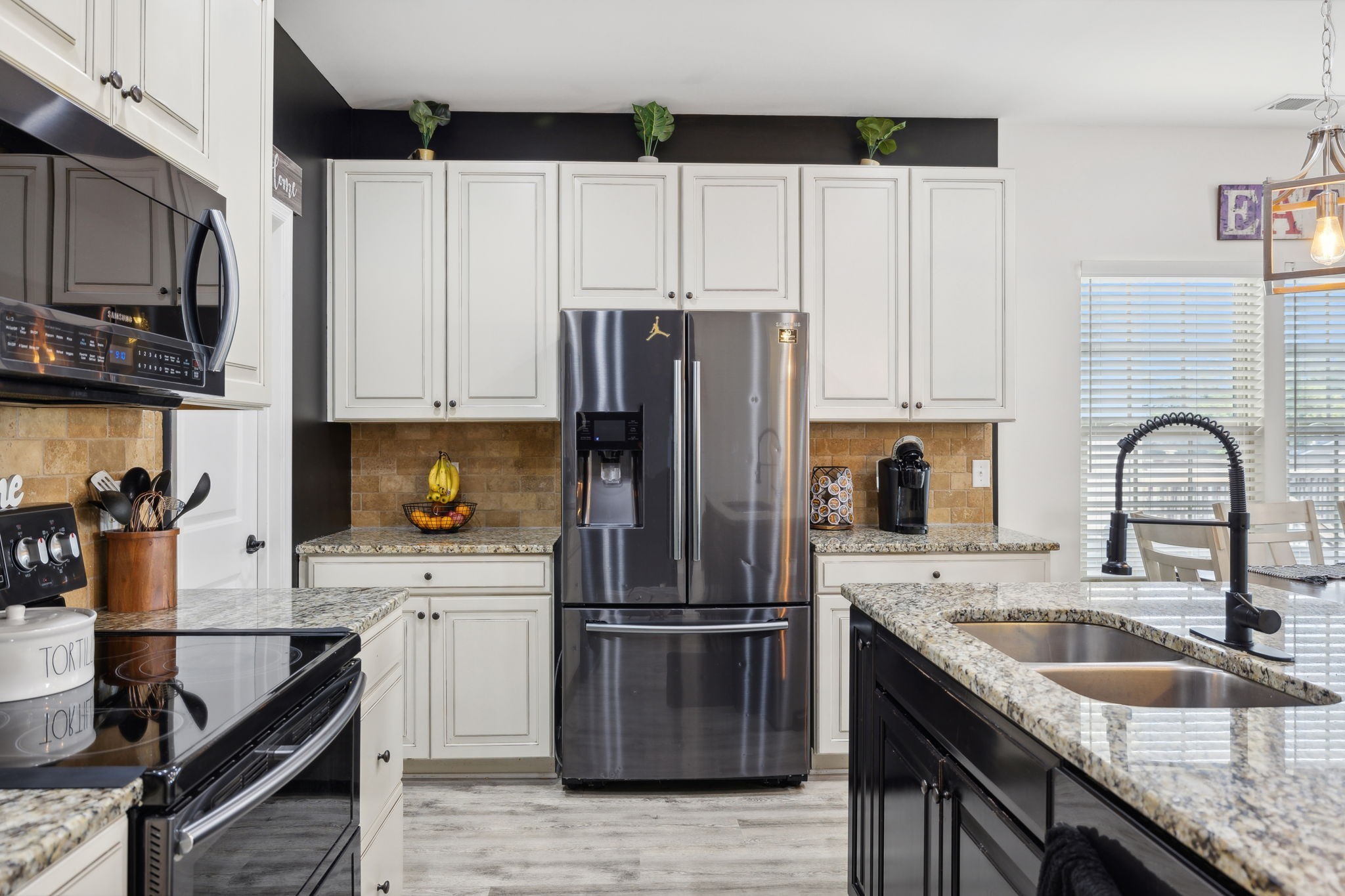 a kitchen with granite countertop a sink stainless steel appliances and white cabinets