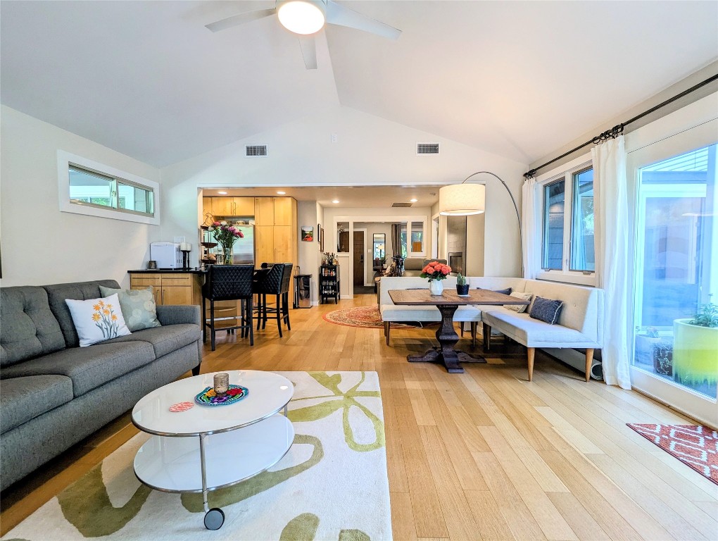 a living room with furniture and a dining table with wooden floor