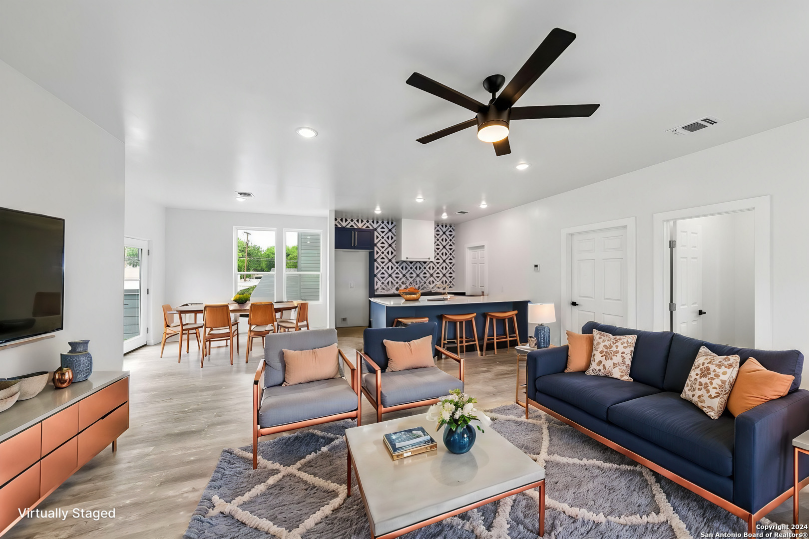 a living room with furniture kitchen view and a flat screen tv