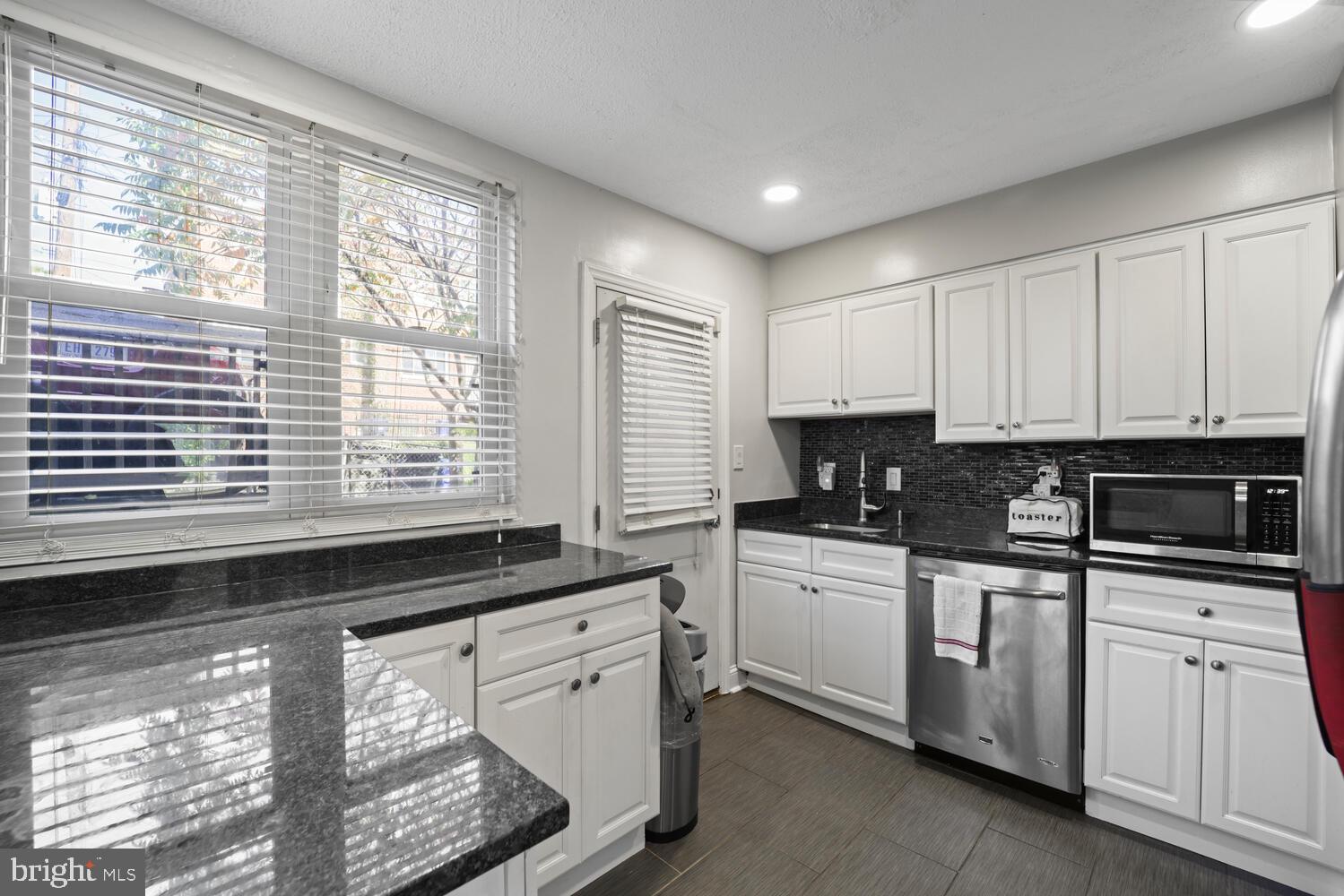 a kitchen with granite countertop white cabinets and a window