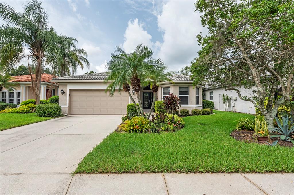 a front view of a house with a garden and palm trees