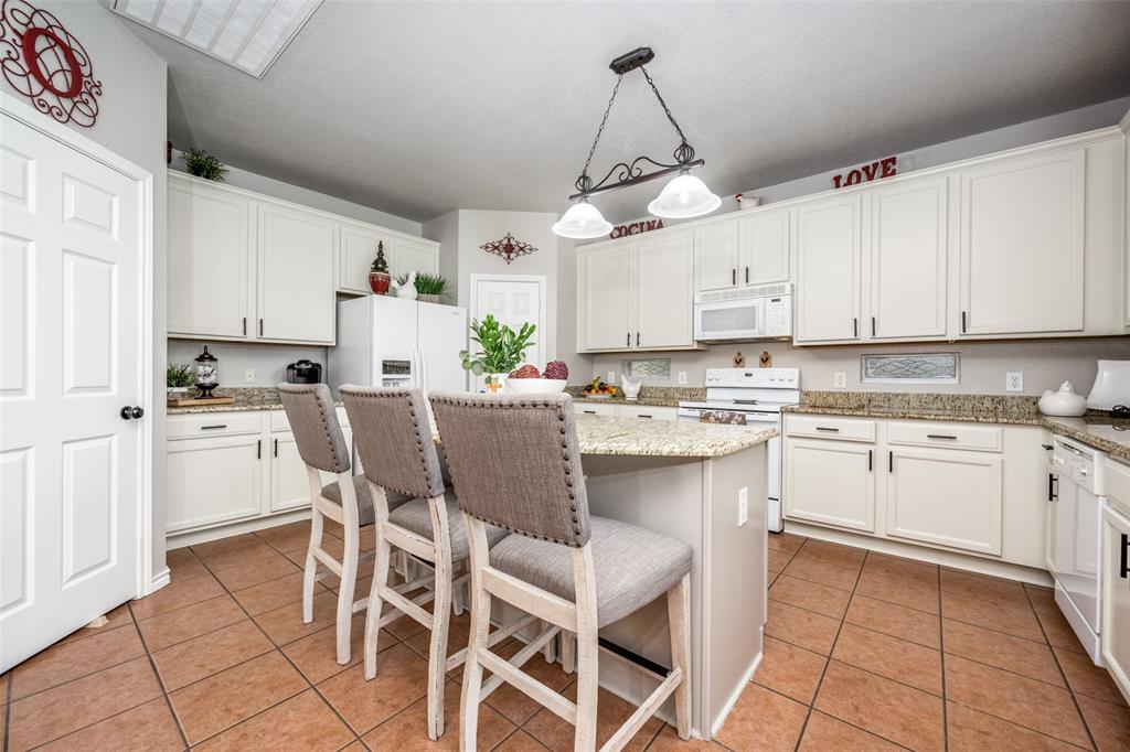 a kitchen with stainless steel appliances granite countertop a sink a stove a refrigerator cabinets and chairs