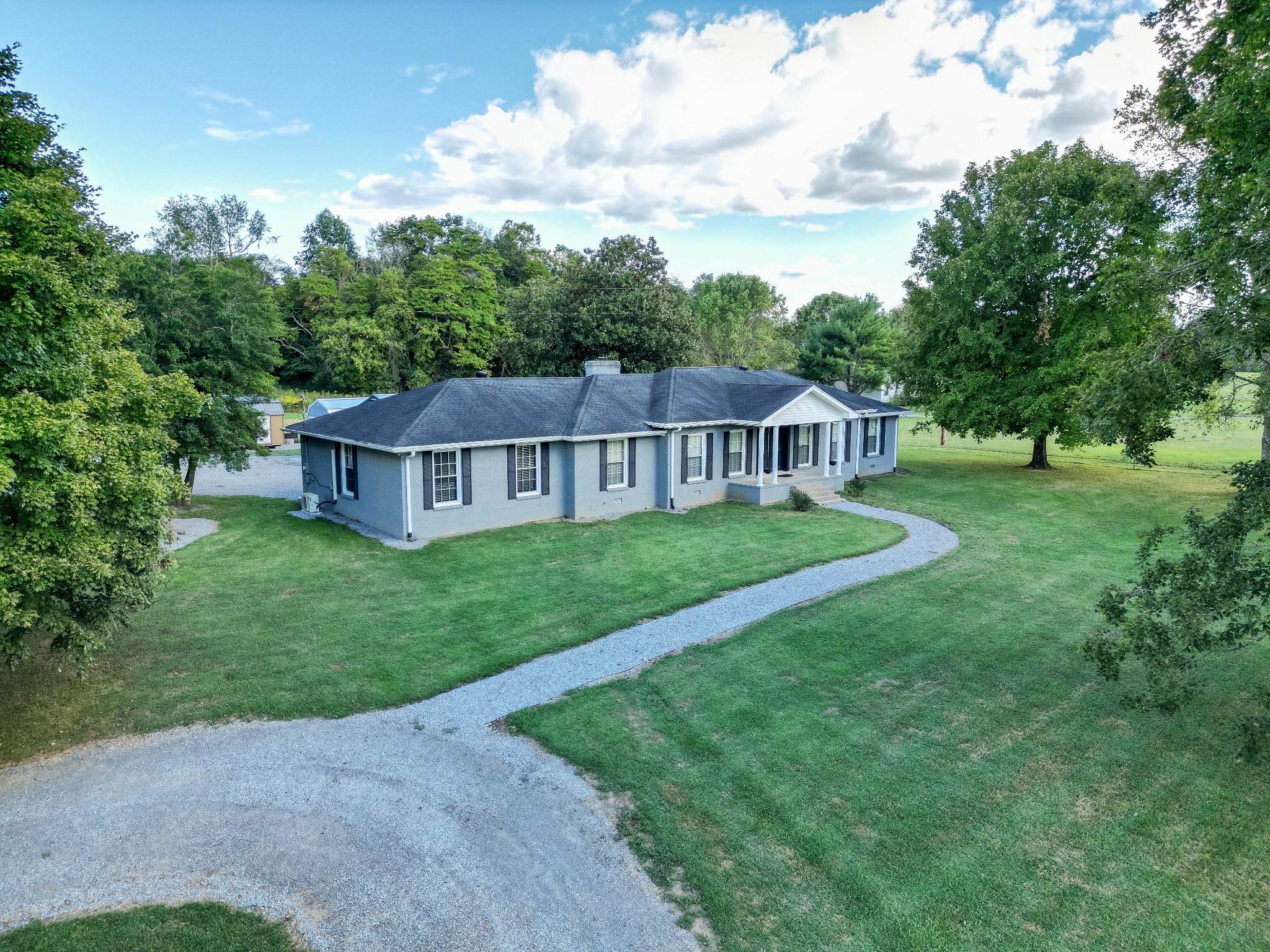 a view of a house with a big yard and large trees