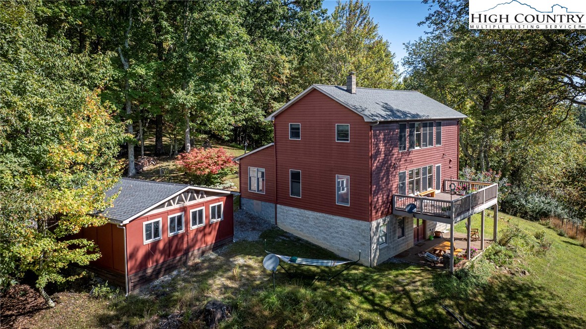 an aerial view of a house with yard and trees in the background