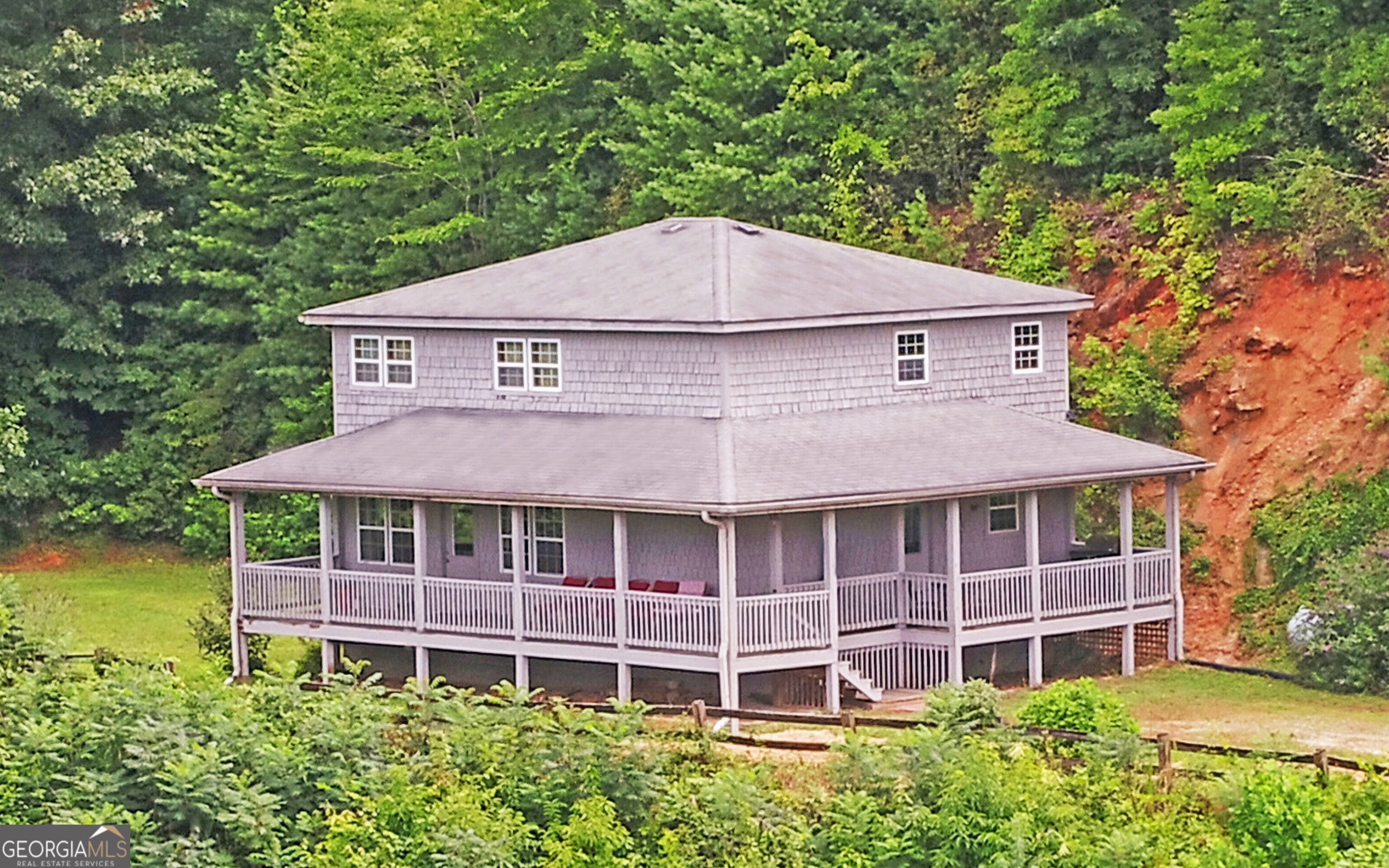 a view of a house with a yard plants and large tree