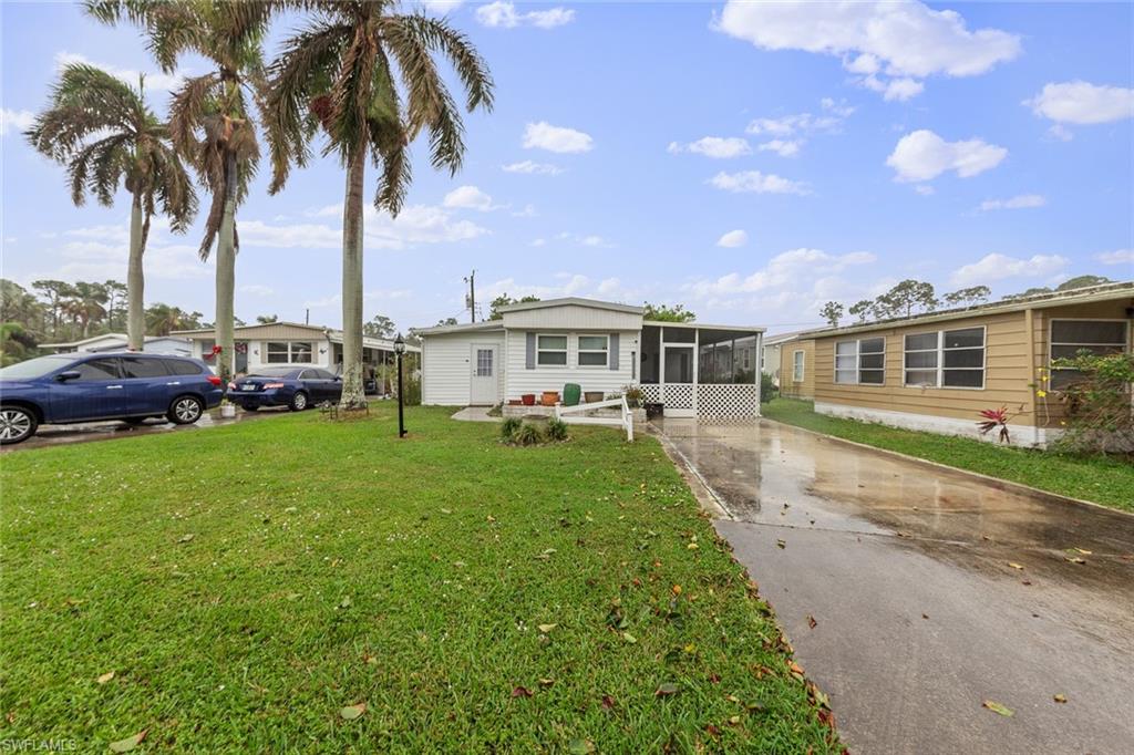 Manufactured / mobile home featuring a front lawn and a sunroom