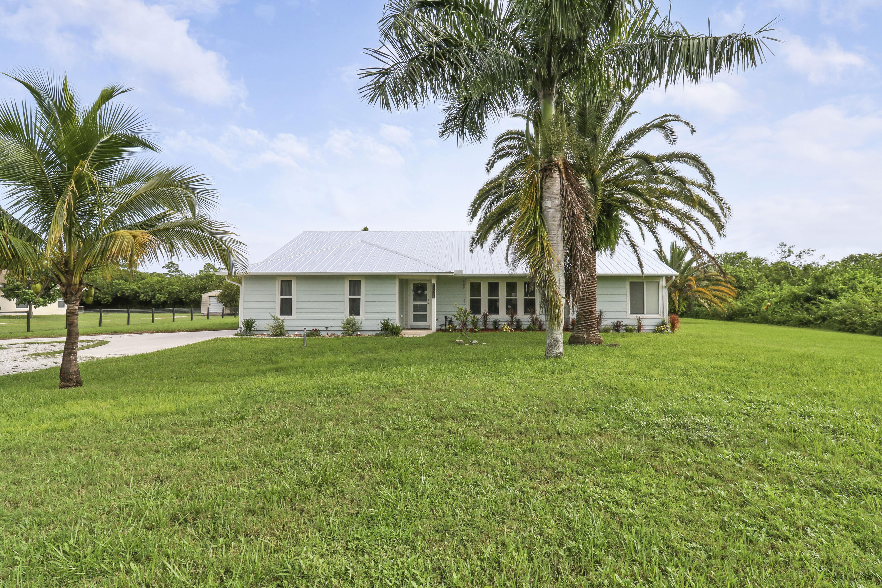 a view of a house with a big yard and palm trees