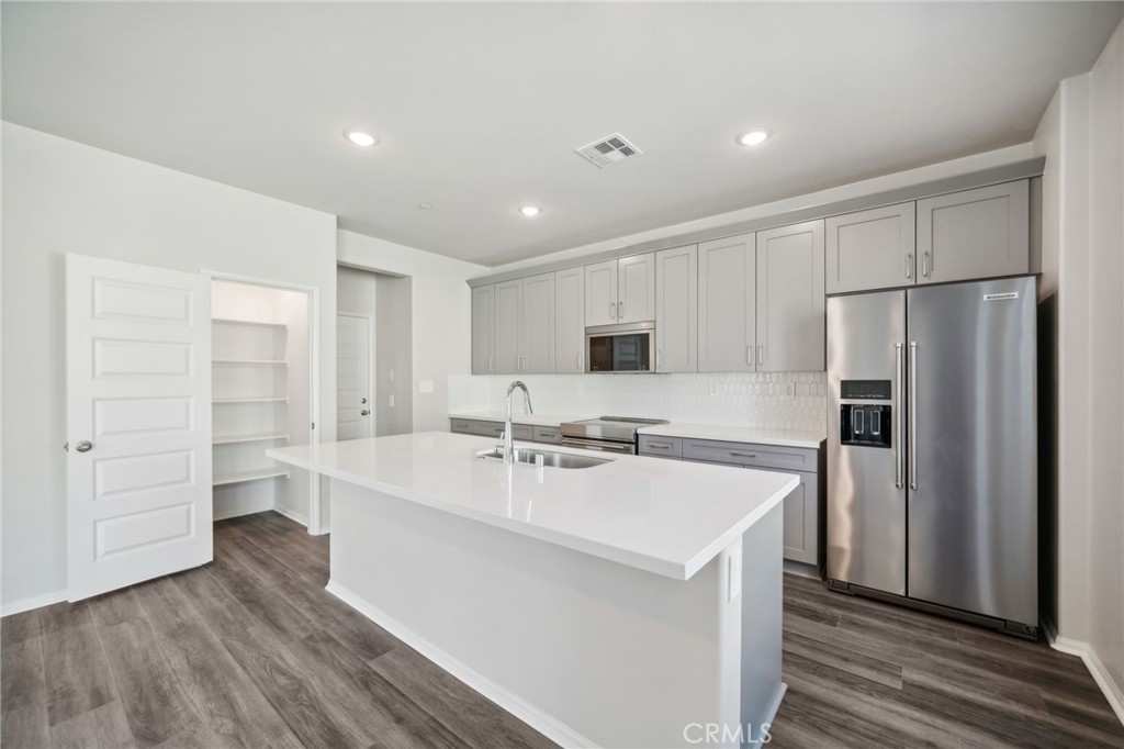 a kitchen with a refrigerator a sink and dishwasher with wooden floor