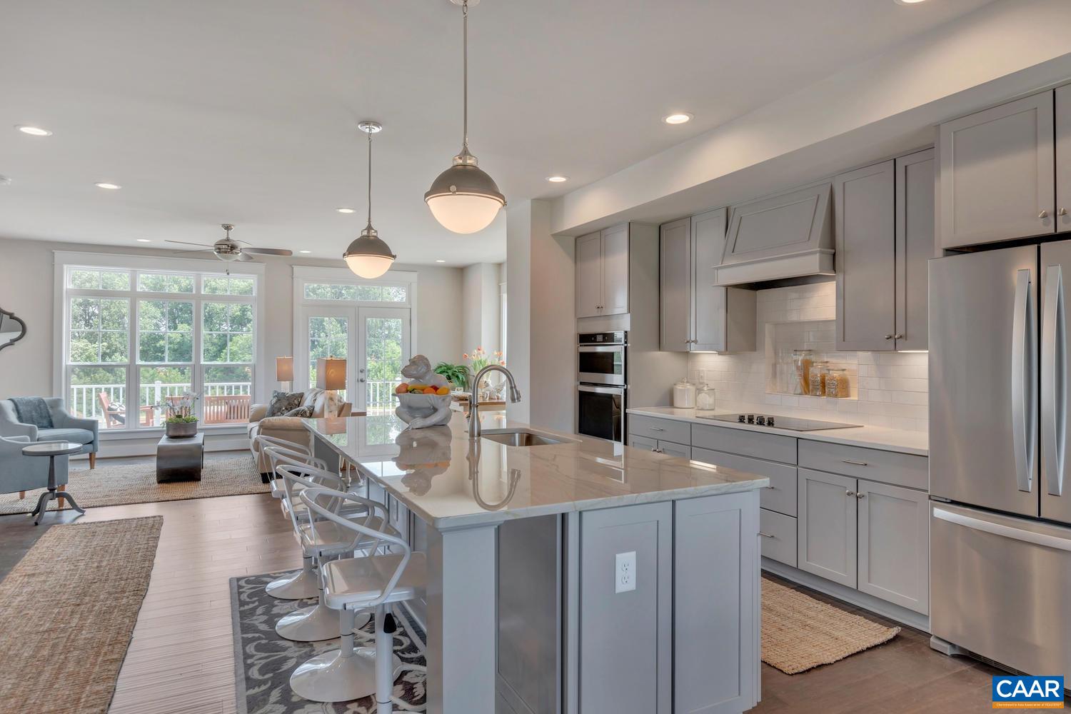 a very nice looking open dining room with kitchen island furniture a large window and a refrigerator