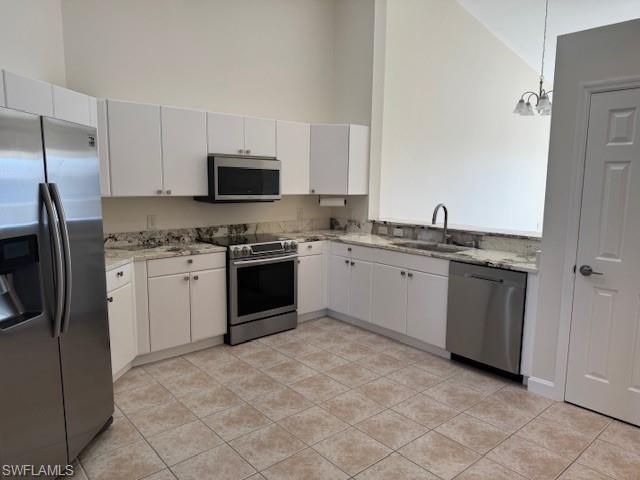 Kitchen featuring white cabinetry, pendant lighting, stainless steel appliances, and sink