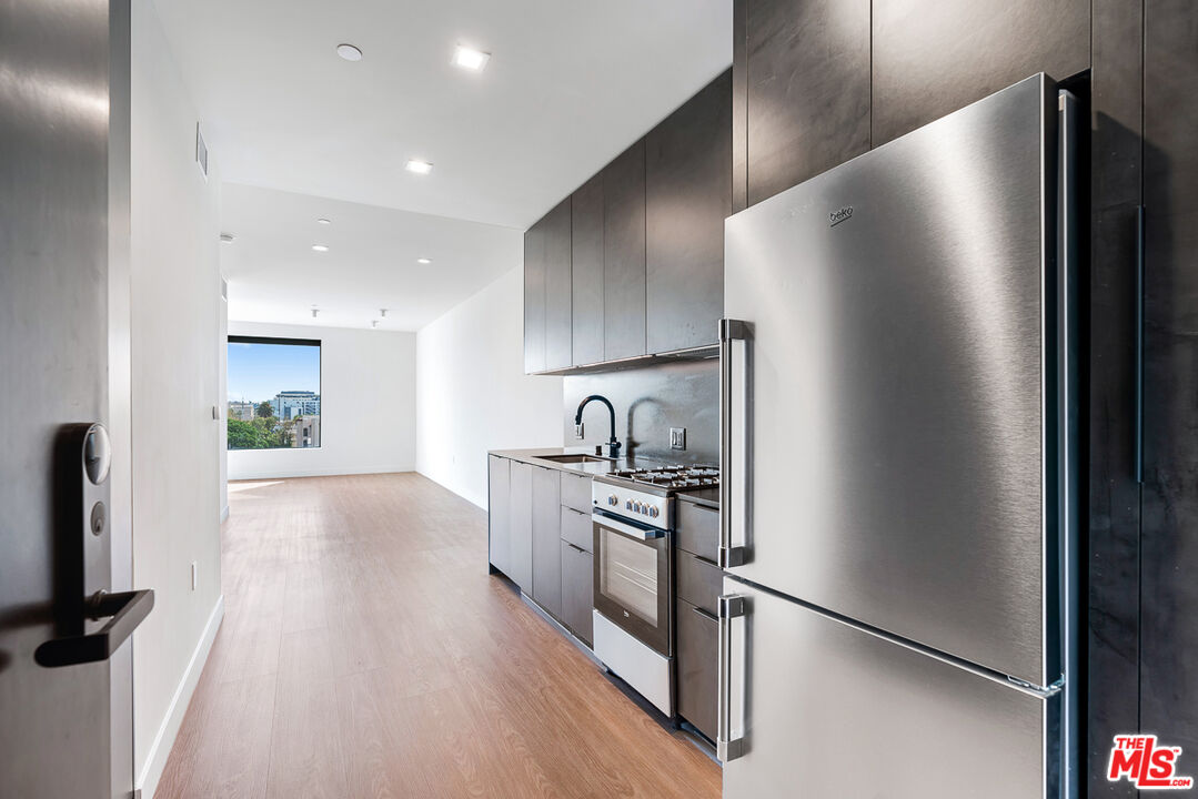 a kitchen with stainless steel appliances granite countertop a refrigerator and a stove top oven