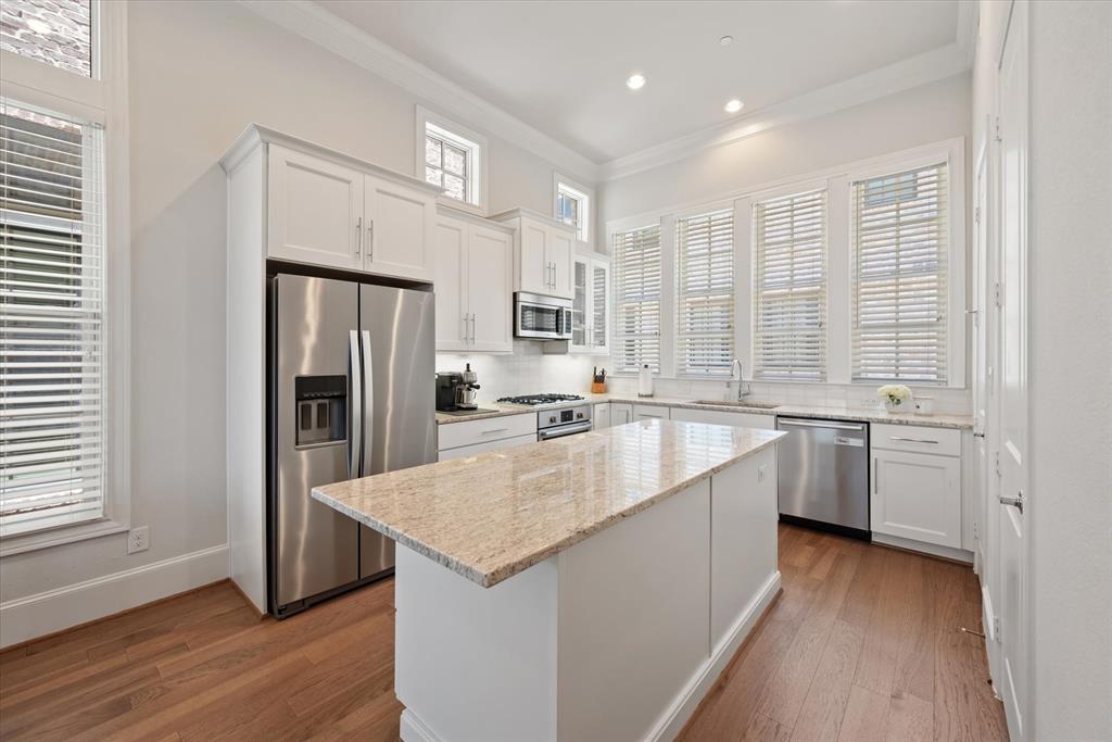 a large kitchen with a center island wooden floor and stainless steel appliances