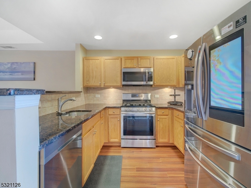 a kitchen with stainless steel appliances granite countertop a sink stove microwave and refrigerator