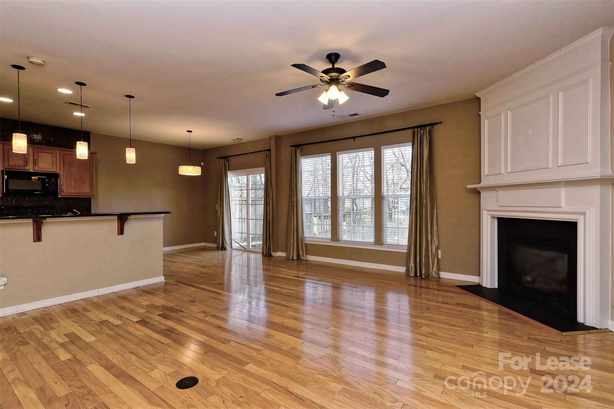 a view of an empty room with window and wooden floor