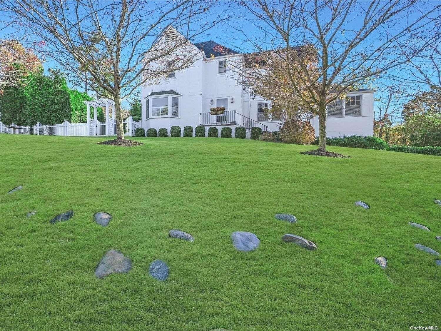 a backyard of a house with plants and large tree