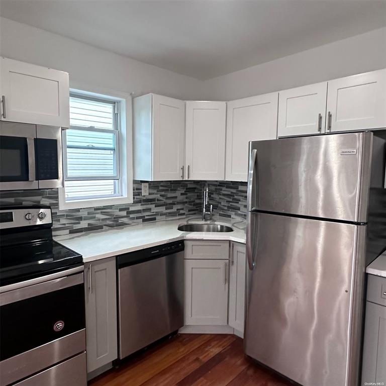 a kitchen with stainless steel appliances a refrigerator a stove a sink and white cabinets