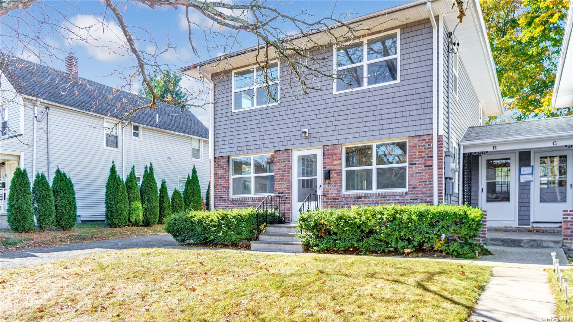 a view of a house with brick walls plants and large tree