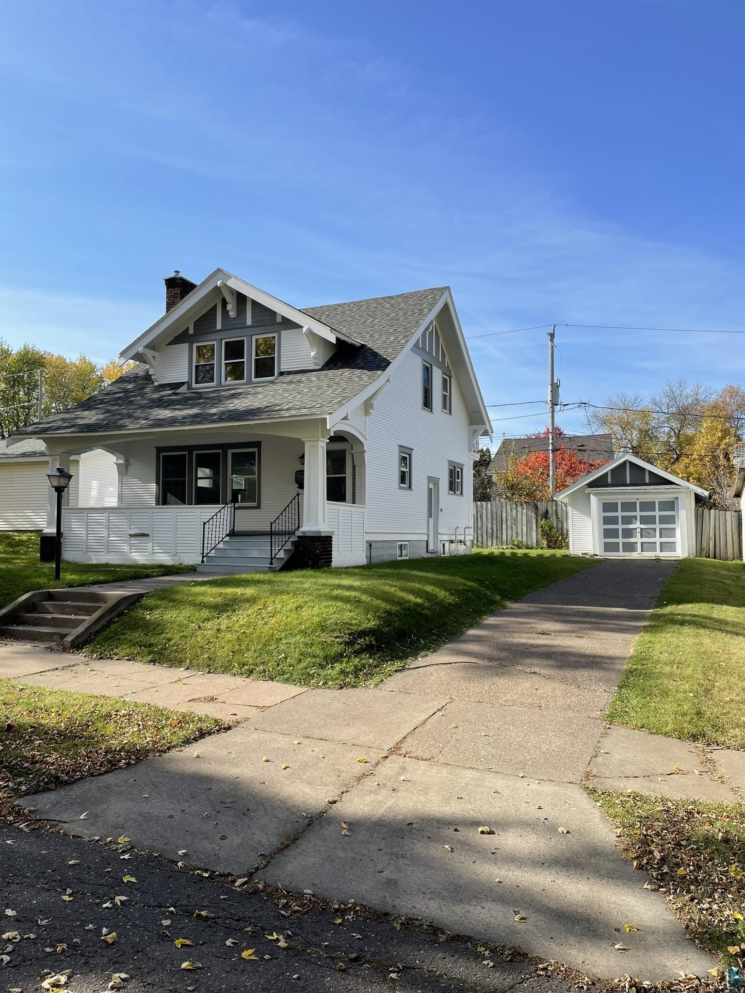 View of front of home with a front yard, an outdoor structure, and a garage