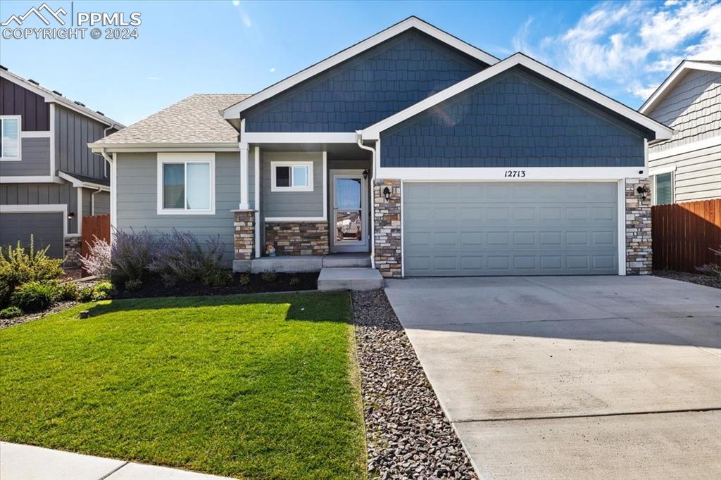 View of front of property with a garage and a front lawn