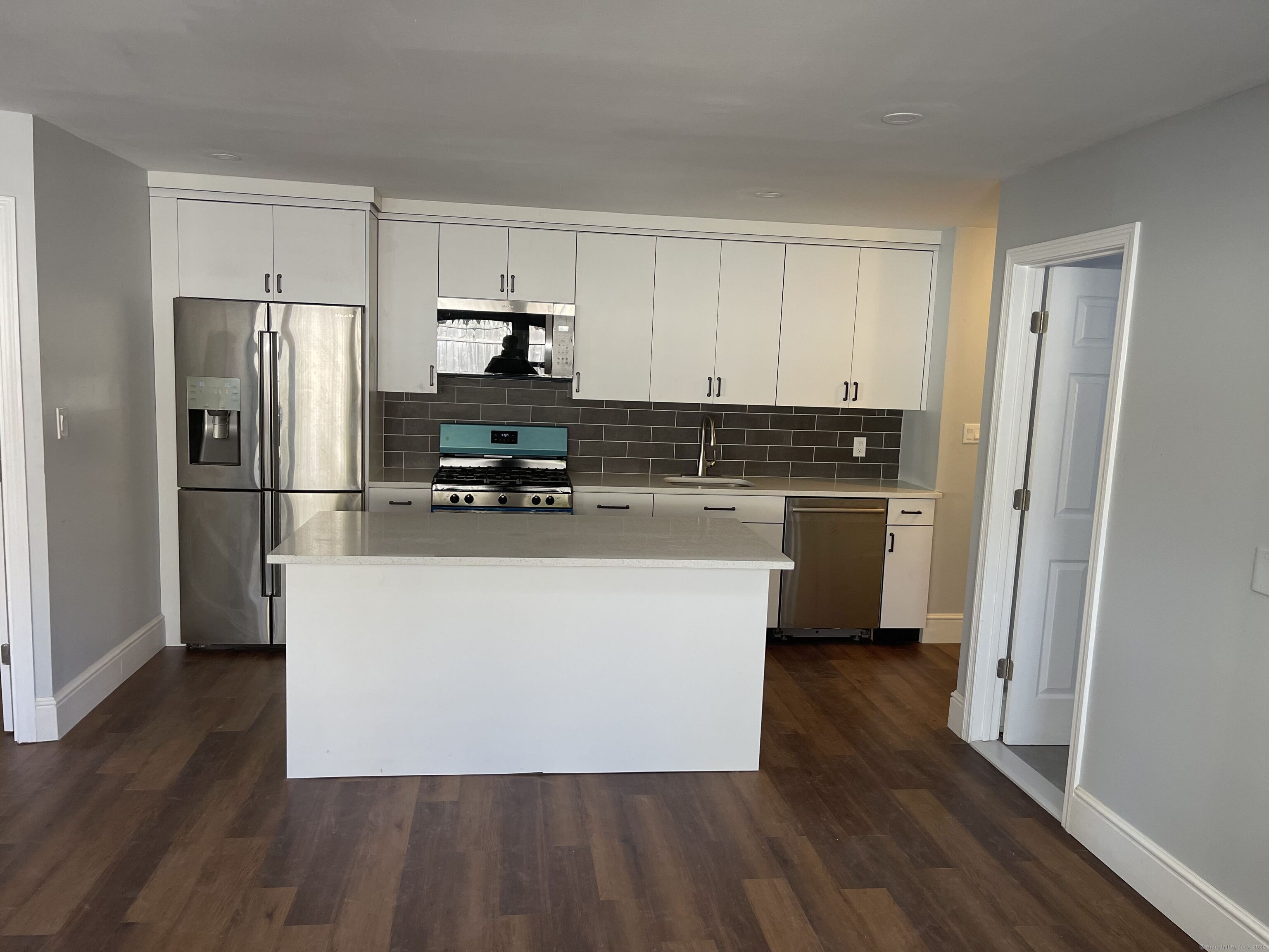 a kitchen with stainless steel appliances a refrigerator stove and wooden floor