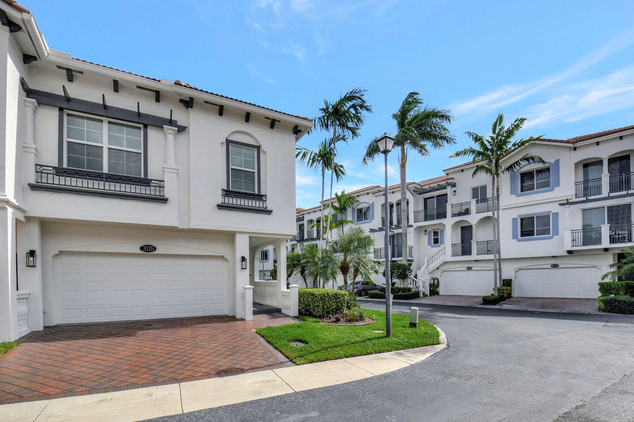 a view of a white building among the street with palm trees