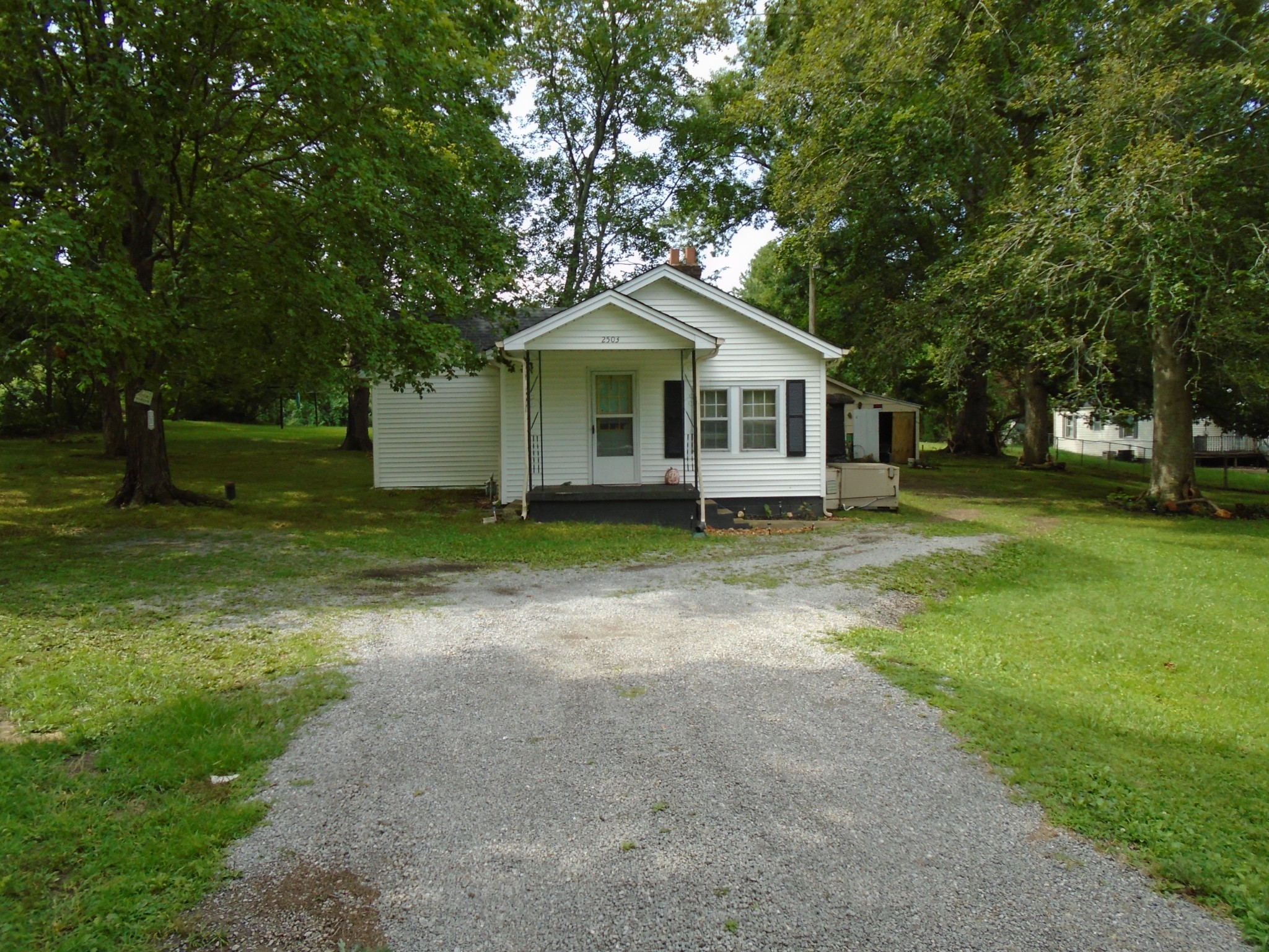 a front view of a house with a garden and trees