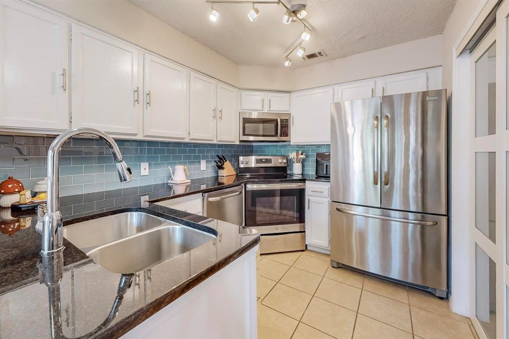 a kitchen with granite countertop a refrigerator a sink a stove and cabinets