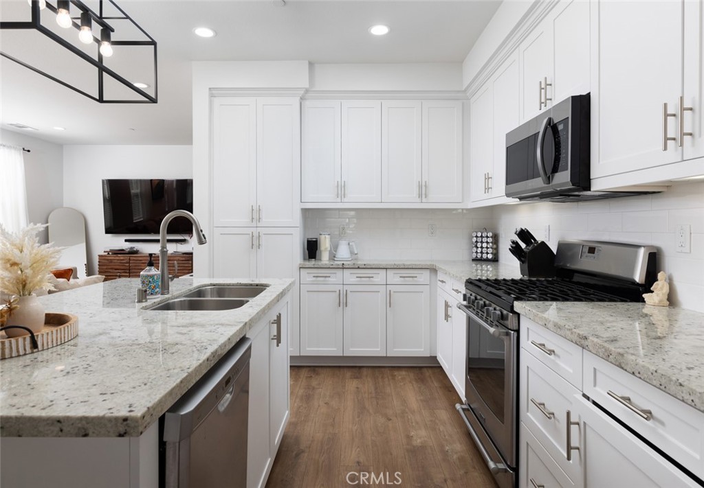 a kitchen with stainless steel appliances granite countertop a sink dishwasher stove and microwave with wooden floor