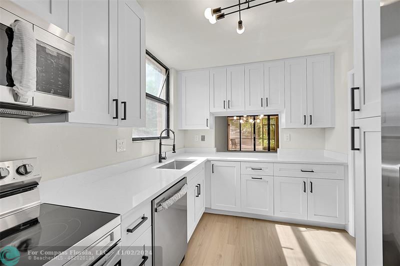 a kitchen with granite countertop a sink a stove and cabinets